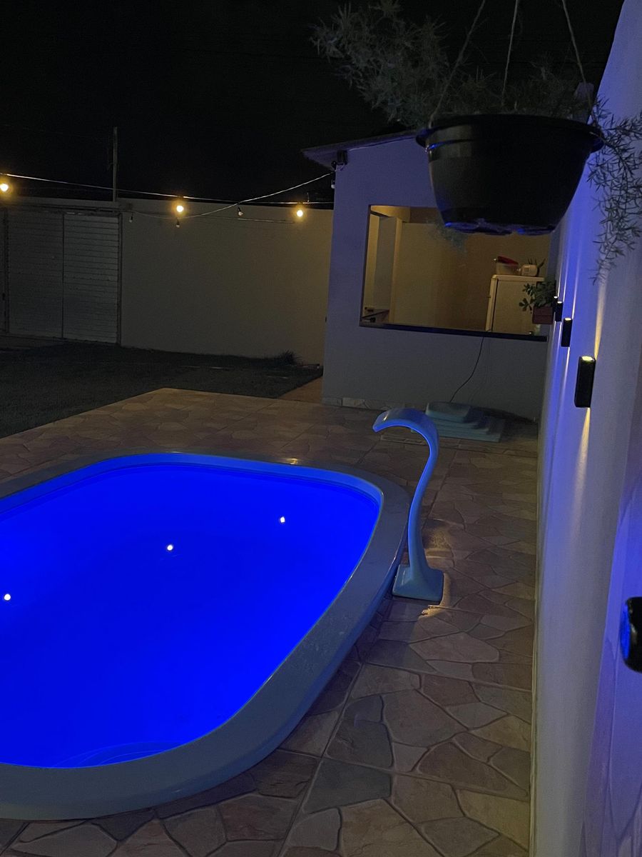 A piscina de noite com a cascata e a área coberta ao fundo