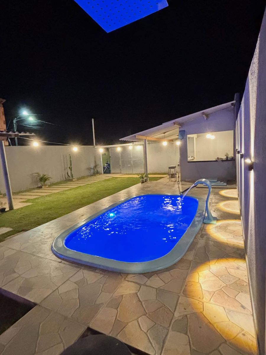O quintal de noite: piscina acesa, gramado e o varal de luzes