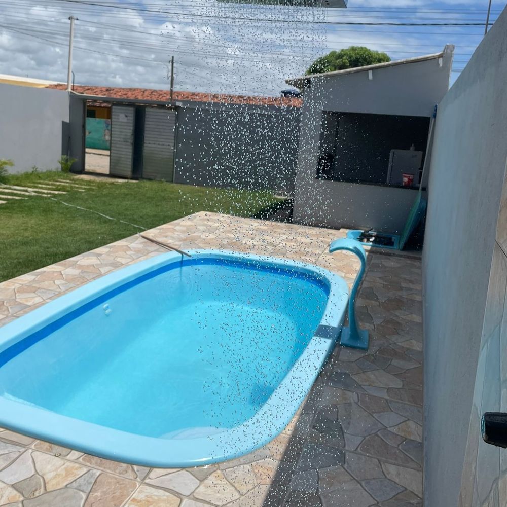 A piscina de dia, com o chuveirão caindo na água