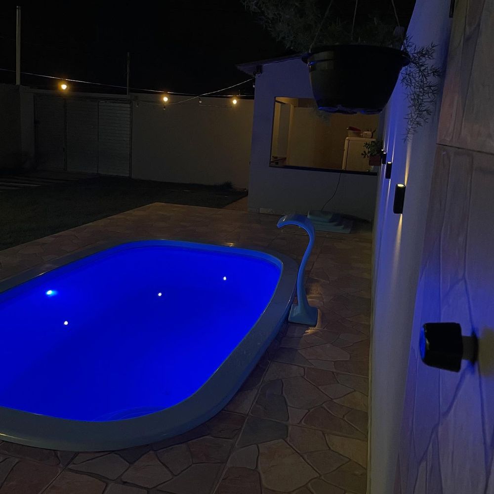 A piscina de noite, acesa em azul, com a cascata ao lado